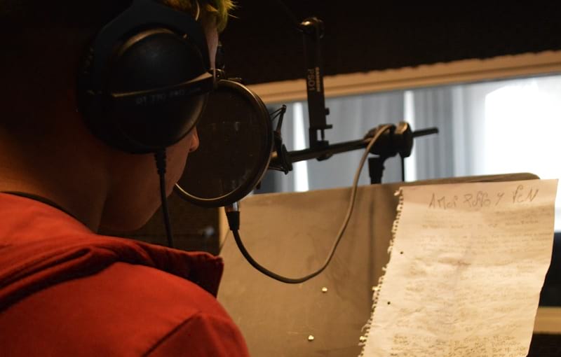 Joven con letra en el atril, cantando 