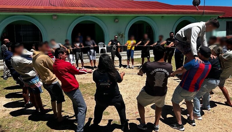 Jóvenes y educadores formando un círculo agarrados de una cuerda