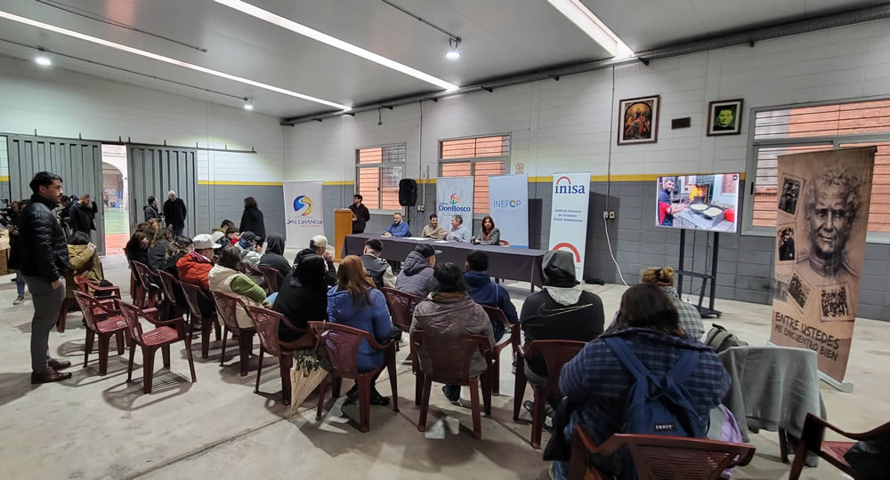 Jóvenes de espalda y mesa con ponentes